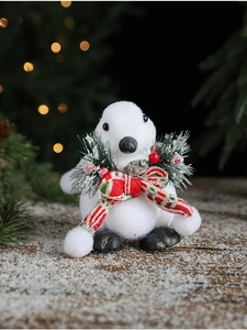 Close-up of white flocked polar bear figurine with festive red bow and pine berry detail