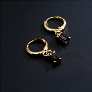 Golden geometric earrings featuring rectangular black zircon pendants on a textured surface