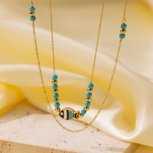 Detail of 18K gold-plated double-layer necklace with enamel fish pendant and blue beads