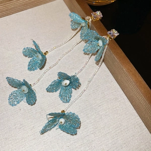 Macro shot of sky blue mesh flower earrings with dangling white bead tassels and crystals