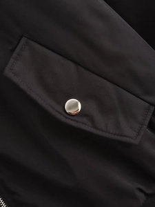Détail de la poche latérale avec bouton-pression en métal argenté sur la veste noire