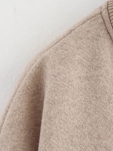Detail shot of the textured beige tweed fabric and high-quality stitching on the jacket
