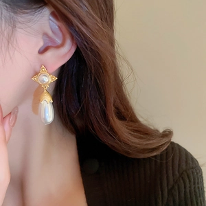 Gros plan de boucles d'oreilles vintage avec étoile dorée et perle goutte portée