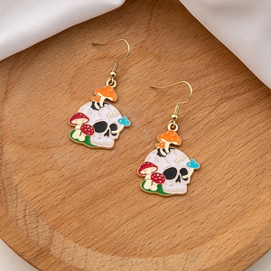 Detailed close-up of gothic skull earrings with colorful mushrooms on a wooden tray