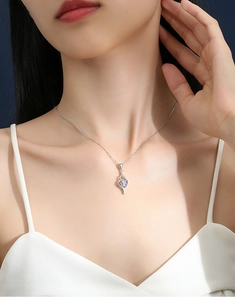 Macro shot of S925 sterling silver necklace featuring a swirling moissanite pendant on neck