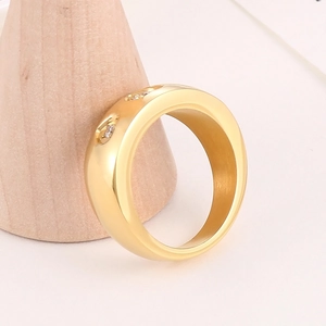Polished gold titanium steel ring with inlaid diamonds on a minimalist wood stand