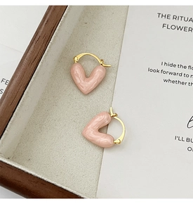 Close-up of pink enamel heart earrings with gold hoop on a minimal background