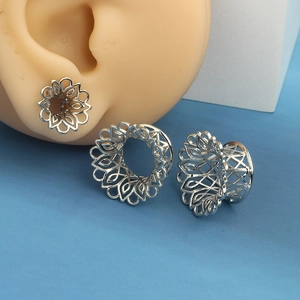 Detailed macro of silver stainless steel ear gauge with intricate hollow mandala pattern