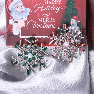 Christmas snowflake brooches with colorful rhinestones and pearls on silver satin fabric
