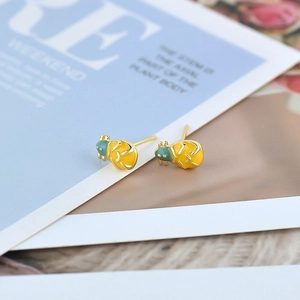 Macro view of insect-shaped stud earrings with yellow and cyan enamel in gold finish