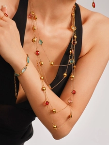 Détail de colliers multicouches plaqués or 18 carats avec pierres en verre colorées