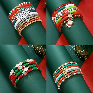 Détail de bracelets de Noël multicouches avec perles d'argile rouges et vertes et breloques