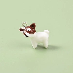 Macro shot of a mini resin puppy charm with brown spots and a metal loop for DIY crafts