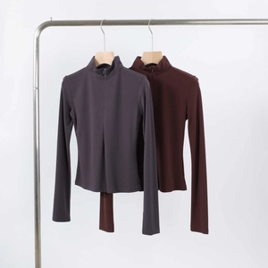 Close-up of slim fit half-zip sports tops in dark grey and brown moisture-wicking fabric