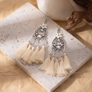 Detail of bohemian tassel earrings with cream fringe and sparkling colorful rhinestones