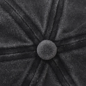 Detail of a black corduroy baseball cap showing the top button and six-panel stitching texture