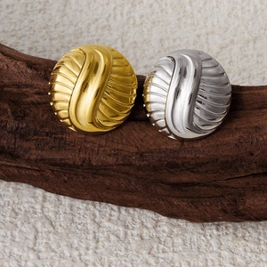 Macro detail of gold and silver striped stainless steel earrings on natural wood stand