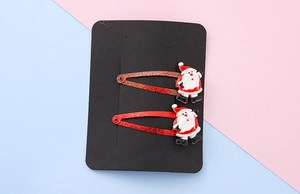 Detail view of two glittery red Christmas tree hair clips with Santa Claus resin charms
