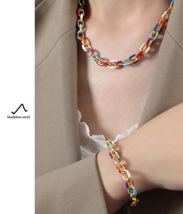 Lifestyle shot of model wearing colorful enamel stainless steel necklace and bracelet set