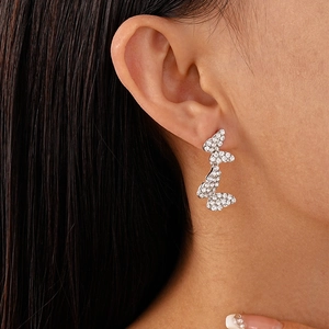 Detailed close-up of butterfly drop earrings with shimmering crystals on model ear