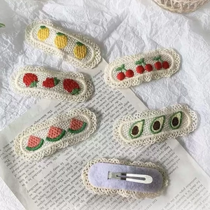 Detailed embroidery on lace fruit hair clips including lemon and strawberry designs