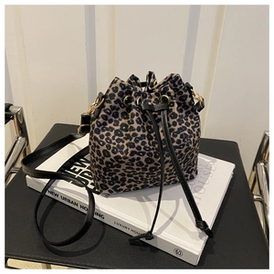 Sac seau chic à imprimé léopard avec cordon noir posé sur un livre dans un salon moderne