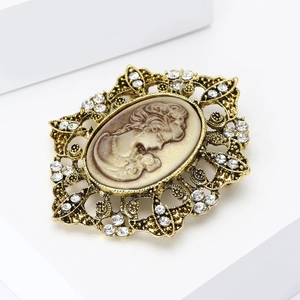 Vintage gold-tone lady portrait brooch with sparkling rhinestones on white surface