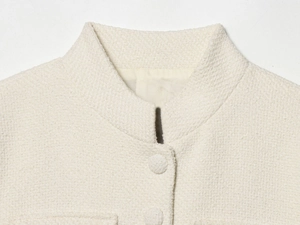 Macro della giacca in tweed crema che mostra trama, bottoni rivestiti e fodera