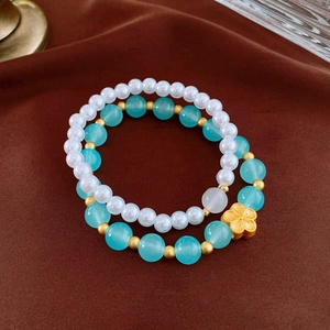 Close-up of vintage flower charms and imitation pearls on a two-piece beaded bracelet set