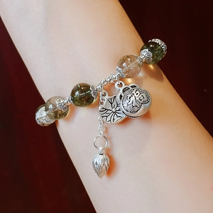 Detailed shot of ethnic agate bracelet with silver Fu character and lotus charms on wrist