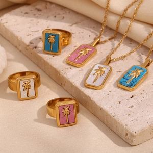 Macro shot of 18K gold-plated necklace and ring set with colorful palm tree pendants