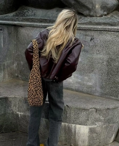 Rear view of deep wine red faux leather biker jacket paired with leopard print shoulder bag
