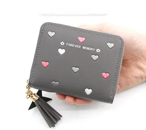 Detail of grey short wallet with heart embroidery, tassel and star charm decoration