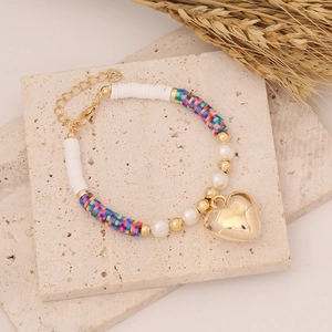 Detailed shot of Bohemian beaded bracelet with gold heart charm and colorful clay discs