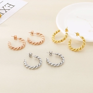 Détail de boucles d'oreilles en C torsadées en finitions or rose, or et argent poli