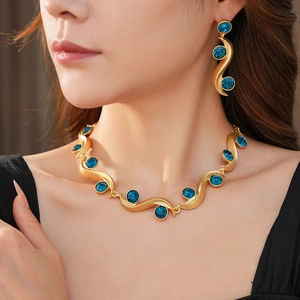 Detail of vintage wavy gold necklace and earrings set with blue crystal rhinestones