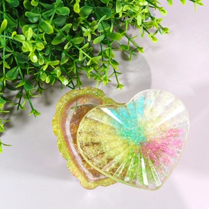 Macro shot of heart-shaped resin storage box with colorful glitter and striped texture