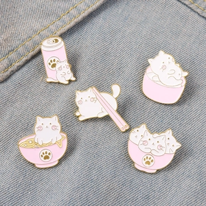Vue détaillée de cinq pins en émail de chat blanc sur fond de tissu denim bleu