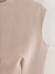 Dettaglio ravvicinato della trama del tessuto a quadri beige di un gilet senza maniche