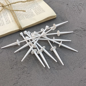 White plastic cake topper base stakes for birthday party decoration on grey surface