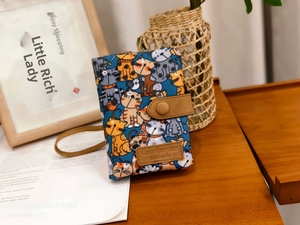 Detail view of cartoon cat fabric wallet with brown leather snap button closure