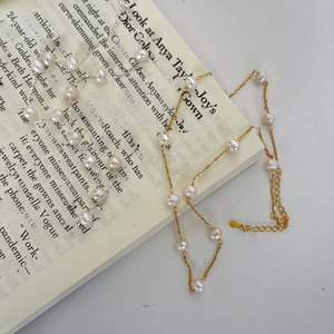 Detail of S925 sterling silver pearl necklaces in gold and silver finishes on book