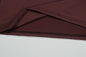 Detail of burgundy dress showing precise overlock stitching and premium fabric texture