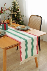 Detail of Christmas table runner with knitted tree patterns and white tassels