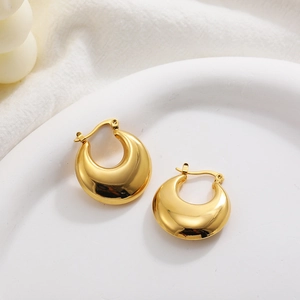 Polished 18K gold chunky hollow hoop earrings resting on a white ceramic plate