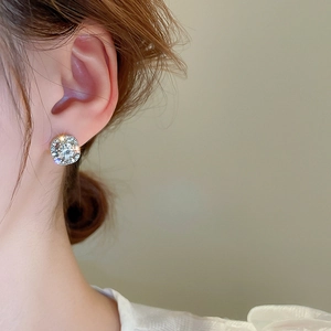 Close-up of a model wearing sparkling round halo stud earrings with silver finish