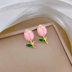 Pink tulip flower earrings with green leaves and gold frame on beige display tray