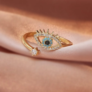 Macro shot of evil eye ring with blue crystals and star on pink silk fabric background