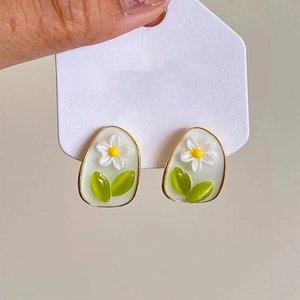 Macro detail of gold-rimmed floral earring with white petals and yellow center