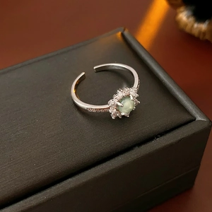 Detail of silver open ring with green zircon sunflower set on black leather jewelry box